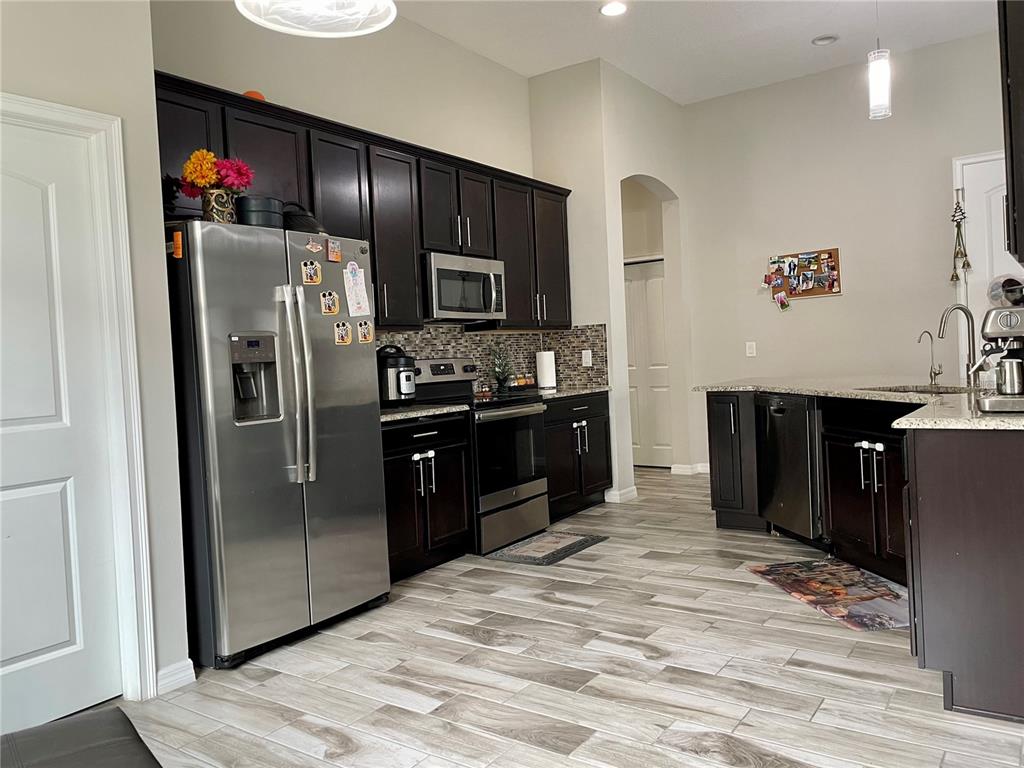 868 Old Windsor Way Spring Hill, FL 34609 - Photo 2 of 20 a kitchen with stainless steel appliances granite countertop a refrigerator and a sink