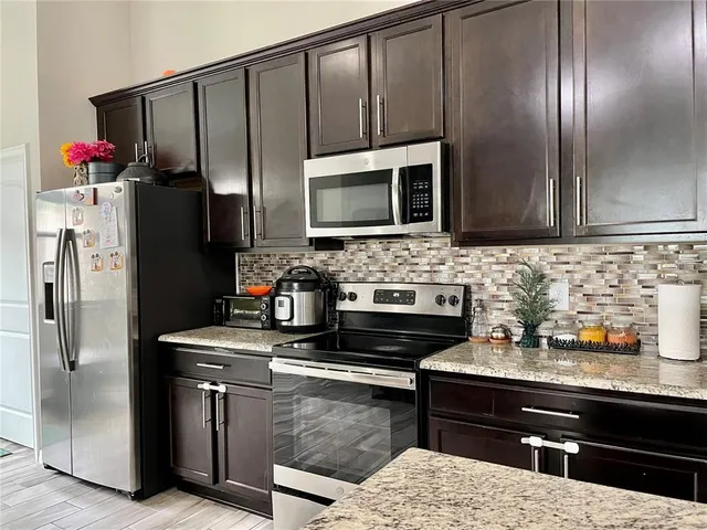 a kitchen with stainless steel appliances kitchen island granite countertop a refrigerator stove and microwave
