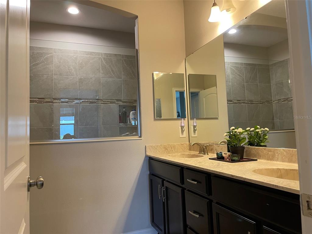 868 Old Windsor Way Spring Hill, FL 34609 - Photo 9 of 20 a bathroom with a double vanity sink a mirror and a shower