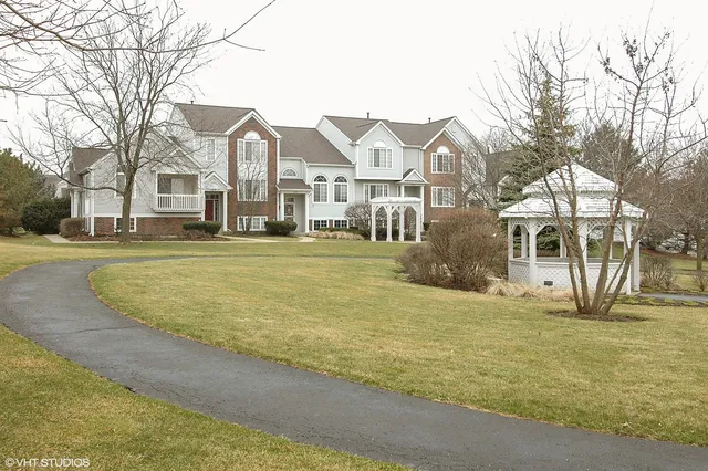 a front view of residential houses with yard and trees in the background