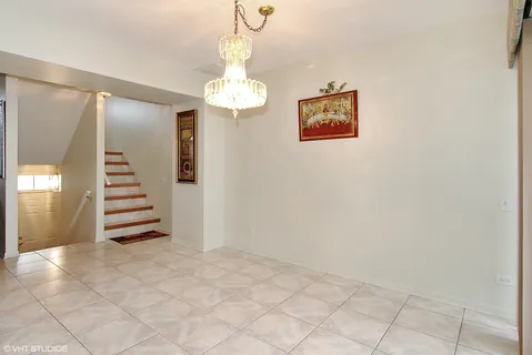 en view of a hallway with stairs and a chandelier