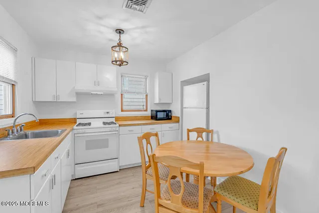 a kitchen with stainless steel appliances granite countertop a sink a stove a dining table and chairs