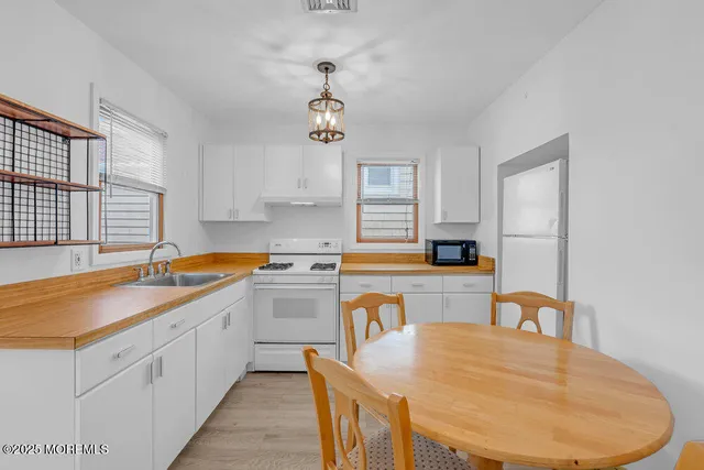 a kitchen with stainless steel appliances granite countertop a sink dishwasher and white cabinets with wooden floor