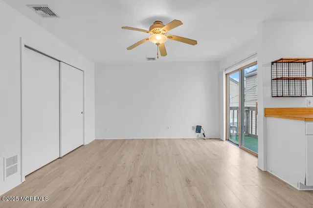 a view of an empty room with window and wooden floor
