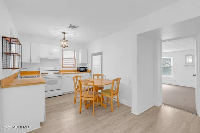 a kitchen with stainless steel appliances kitchen island wooden floors and white cabinets