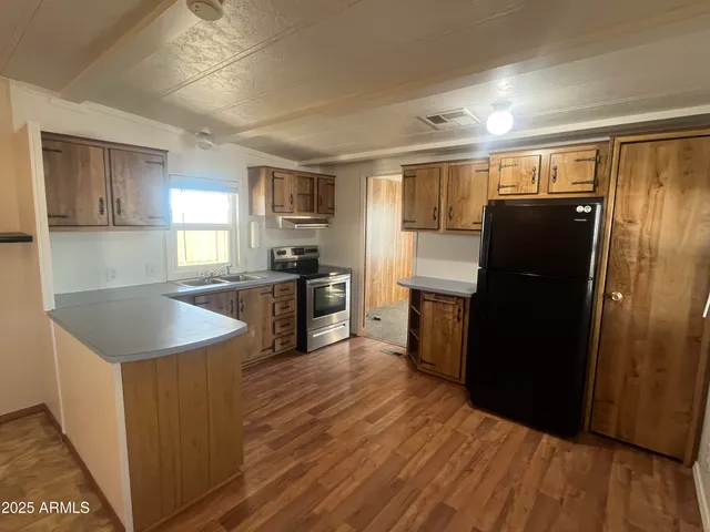 a kitchen with granite countertop a refrigerator a sink a stove and wooden floor