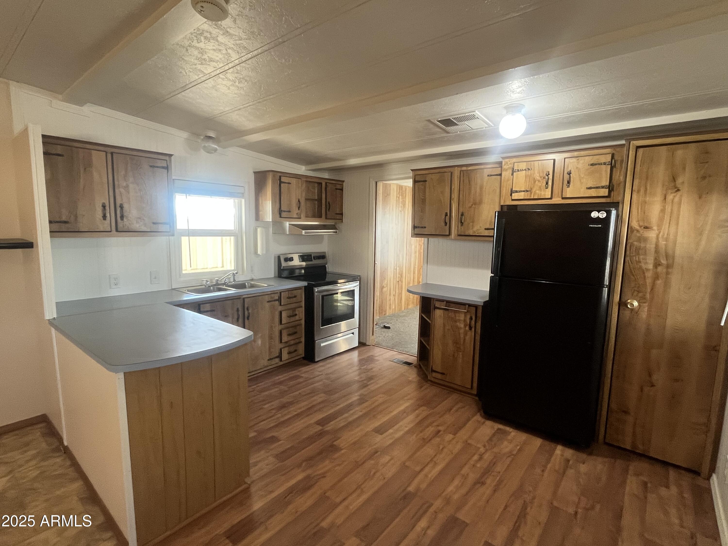 2481 West Broadway Avenue, Unit 31 Apache Junction, AZ 85120 - Photo 8 of 12 a kitchen with granite countertop a refrigerator a sink a stove and wooden floor