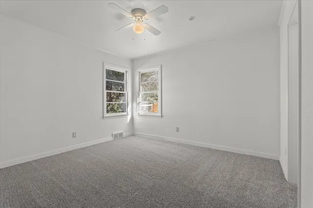 an empty room with windows and fan