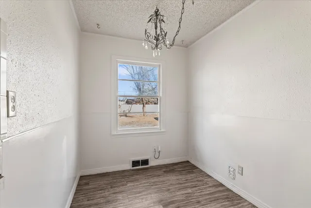 an empty room with wooden floor chandelier and windows