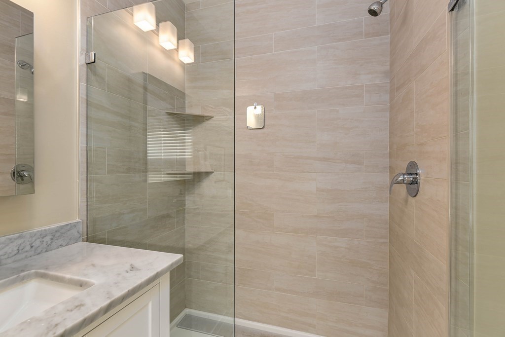 99 Brookley Road, Unit 1 Boston, MA 02130 - Photo 17 of 40 a bathroom with a granite countertop shower a sink and a mirror