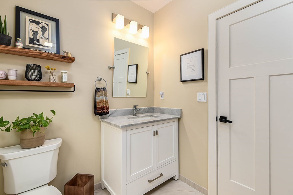 99 Brookley Road, Unit 1 Boston, MA 02130 - Photo 24 of 40 a bathroom with a granite countertop sink a toilet and mirror