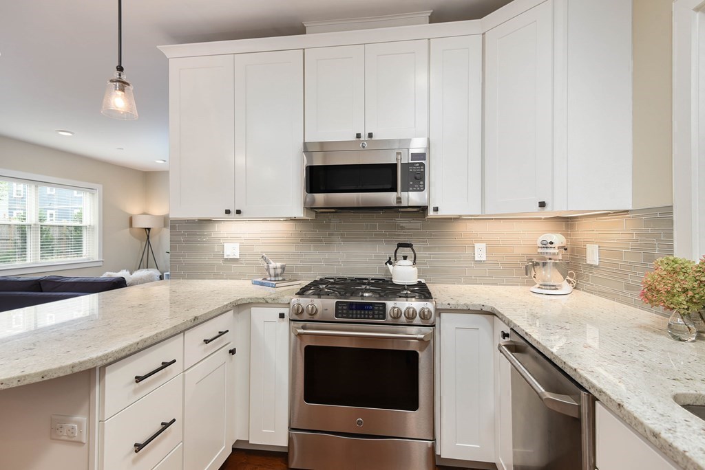 99 Brookley Road, Unit 1 Boston, MA 02130 - Photo 9 of 40 a kitchen with granite countertop white cabinets and a stove top oven