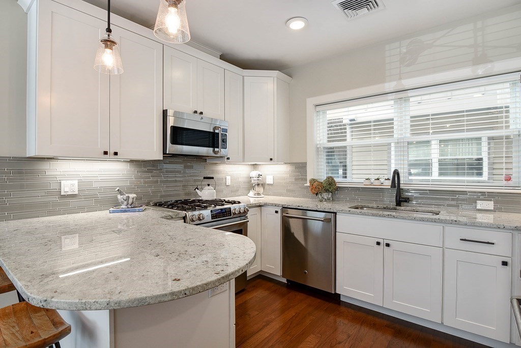 99 Brookley Road, Unit 1 Boston, MA 02130 - Photo 10 of 40 a kitchen with granite countertop white cabinets and a stove