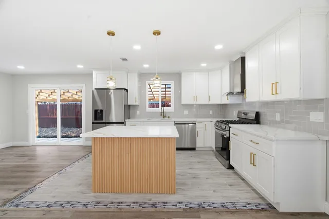 a large kitchen with stainless steel appliances kitchen island granite countertop a stove a sink and a refrigerator