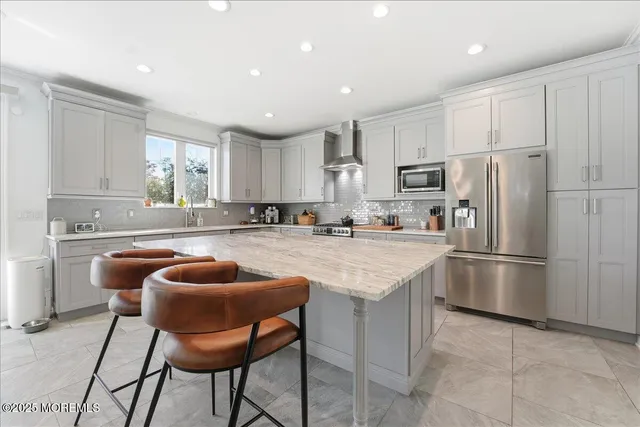 a kitchen with stainless steel appliances granite countertop a refrigerator a sink a stove a dining table and chairs