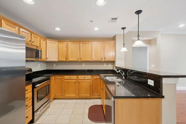 a kitchen with kitchen island granite countertop a sink a counter top space cabinets and stainless steel appliances