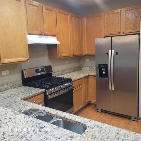 a kitchen with granite countertop a refrigerator stove and cabinets