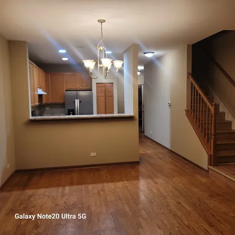 a view of a room with wooden floor and kitchen view