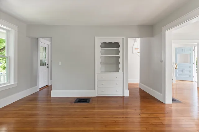 a kitchen with stainless steel appliances granite countertop white cabinets a sink a window and a wooden floors