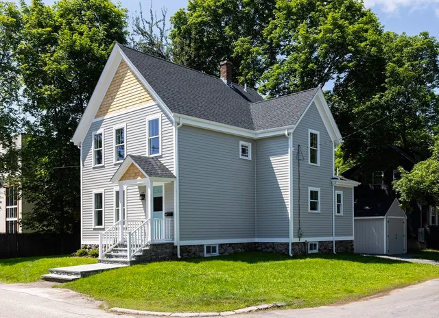 a view of a yard in front of a house with plants and large tree