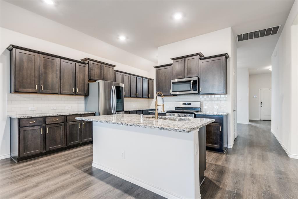 905 Philadelphia Street Fate, TX 75189 - Photo 10 of 25 a kitchen with stainless steel appliances granite countertop a stove top oven a sink and a refrigerator