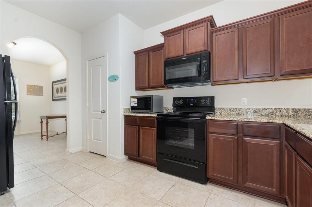 1906 Pilot Point Way Princeton, TX 75407 - Photo 7 of 14 a kitchen with stainless steel appliances granite countertop a stove top oven a sink dishwasher and a refrigerator with wooden cabinets