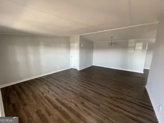 an empty room with wooden floor fireplace and windows