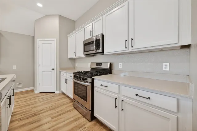a kitchen with stainless steel appliances granite countertop white cabinets and a stove a oven with white countertops