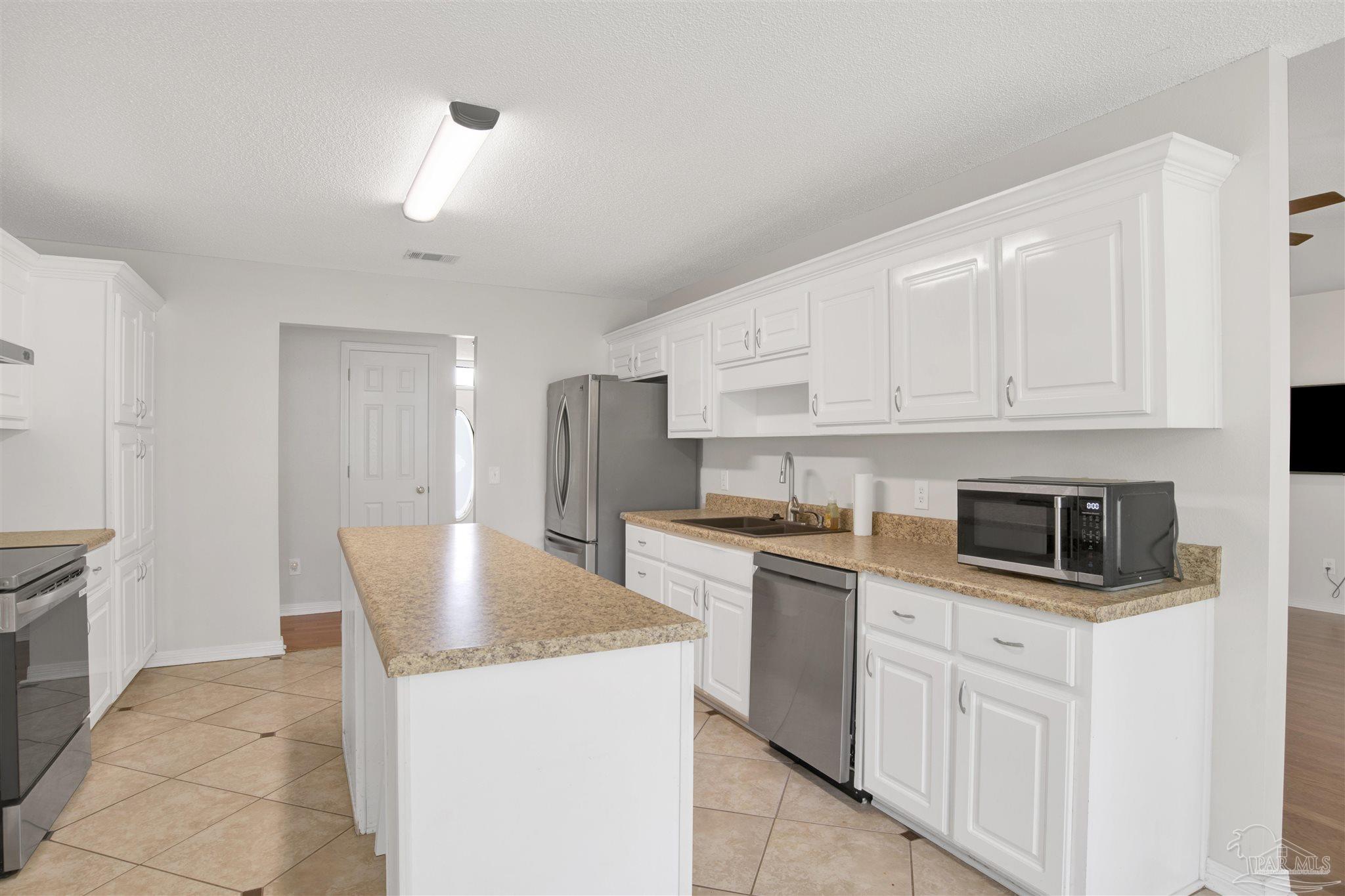 128 Gunwale Road Pensacola, FL 32507 - Photo 12 of 34 a kitchen with stainless steel appliances granite countertop a stove a refrigerator a sink and white cabinets