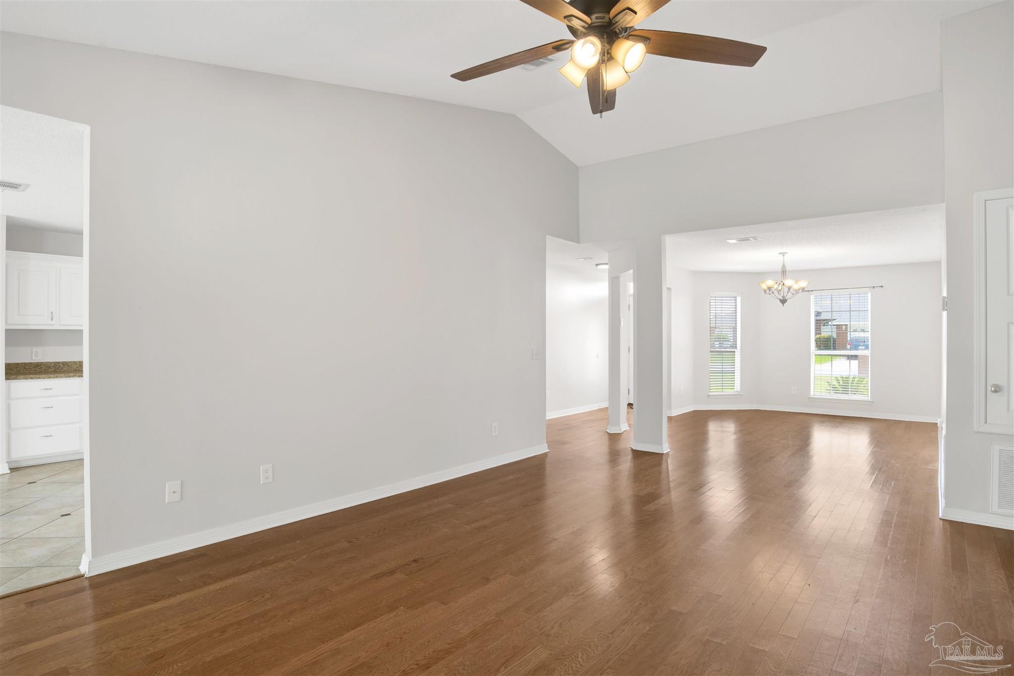 128 Gunwale Road Pensacola, FL 32507 - Photo 9 of 34 an empty room with wooden floor chandelier fan and windows