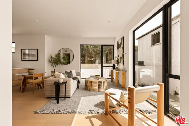 a living room with furniture large window and wooden floor