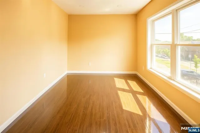 a view of an empty room with wooden floor and a bathroom