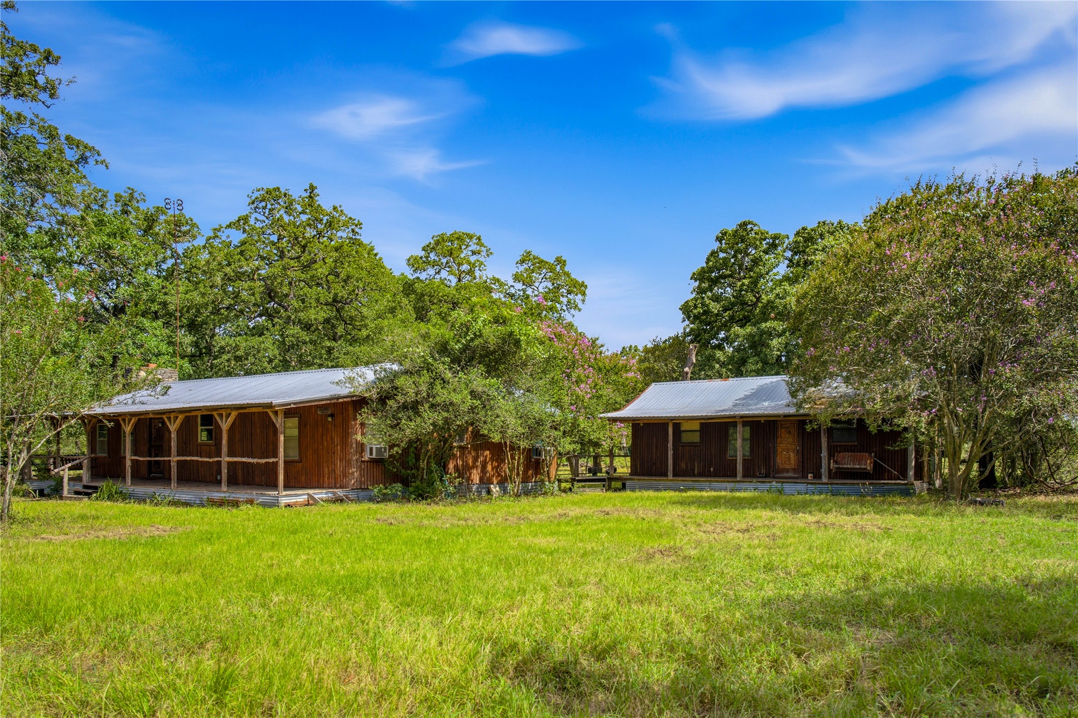 7221 West Old Lockhart Road Muldoon, TX 78949 - Photo 9 of 38 Rustic wooden cabins rest in a peaceful clearing surrounded by mature shade trees.