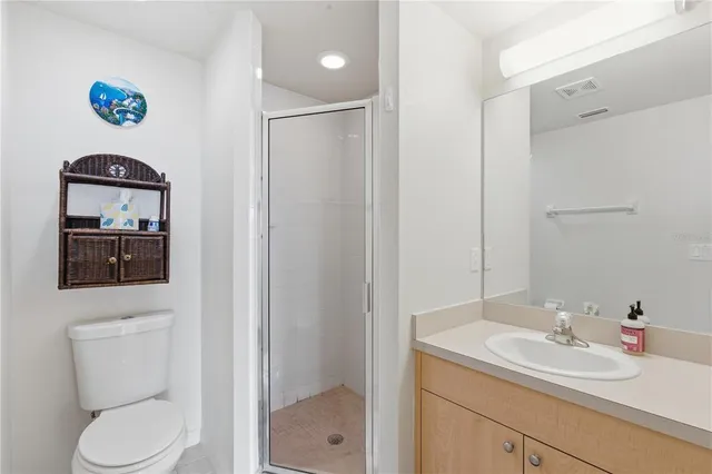 a bathroom with a toilet sink vanity granite and shower