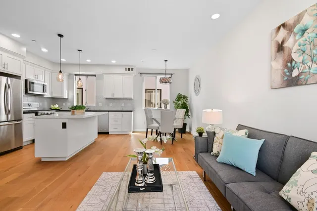 a living room with stainless steel appliances furniture and a kitchen view