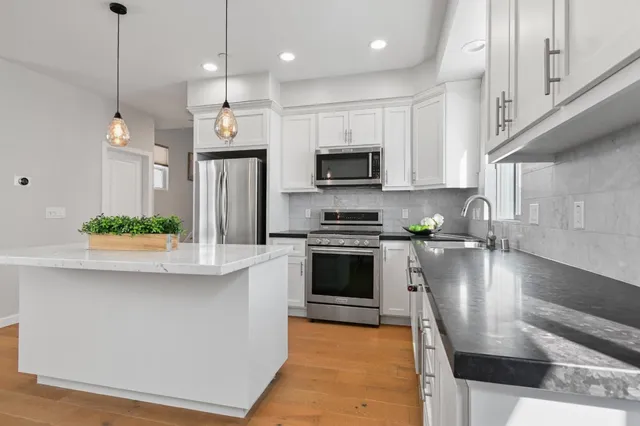 a kitchen with stainless steel appliances granite countertop a sink a stove and a refrigerator