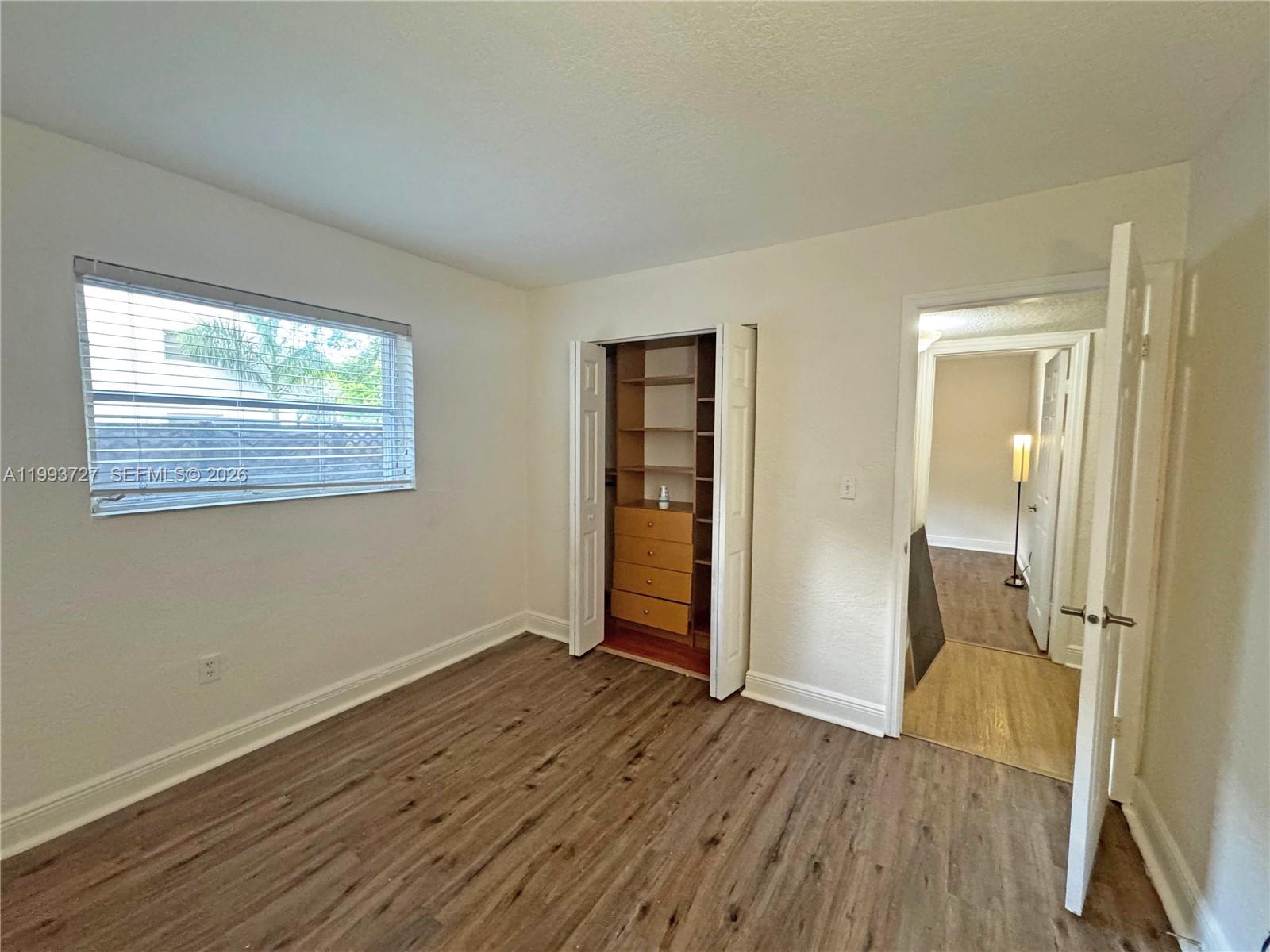 8475 Southwest 94th Street, Unit 119E Miami, FL 33156 - Photo 11 of 15 a view of an empty room with wooden floor and a window