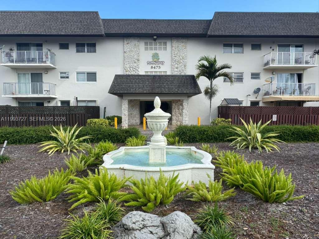 8475 Southwest 94th Street, Unit 119E Miami, FL 33156 - Photo 13 of 15 a front view of a house with a fountain plants and large tree