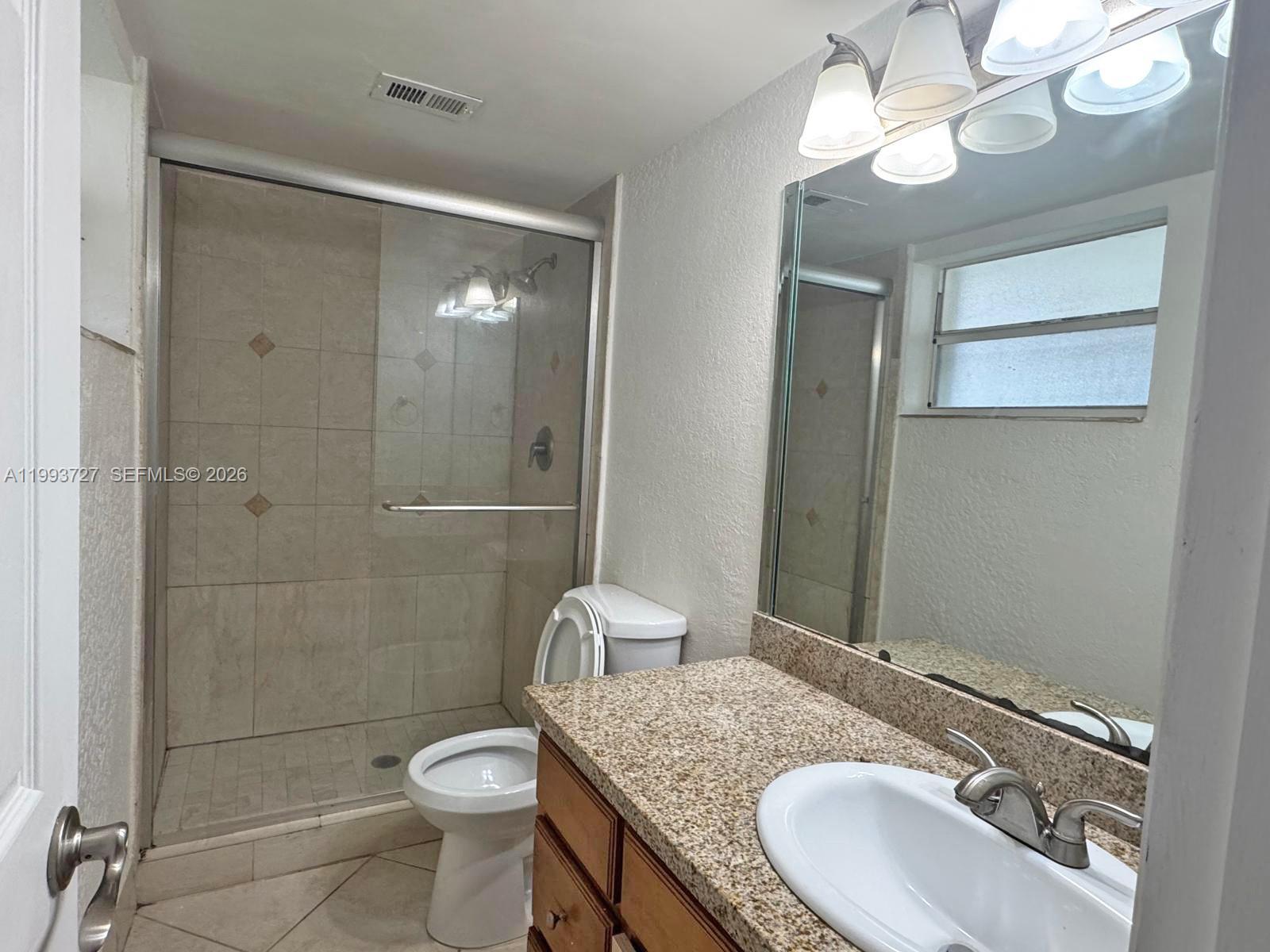 8475 Southwest 94th Street, Unit 119E Miami, FL 33156 - Photo 7 of 15 a bathroom with a granite countertop sink toilet a mirror and shower
