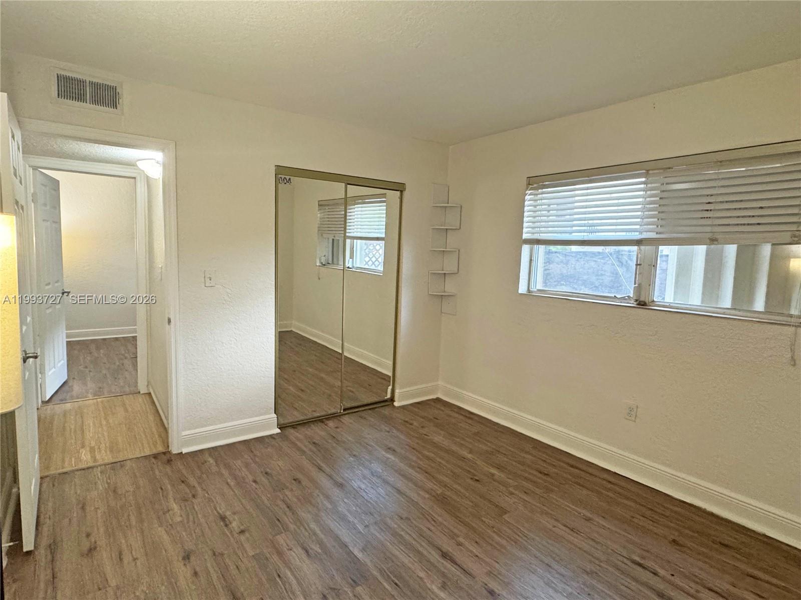 8475 Southwest 94th Street, Unit 119E Miami, FL 33156 - Photo 10 of 15 an empty room with wooden floor and windows