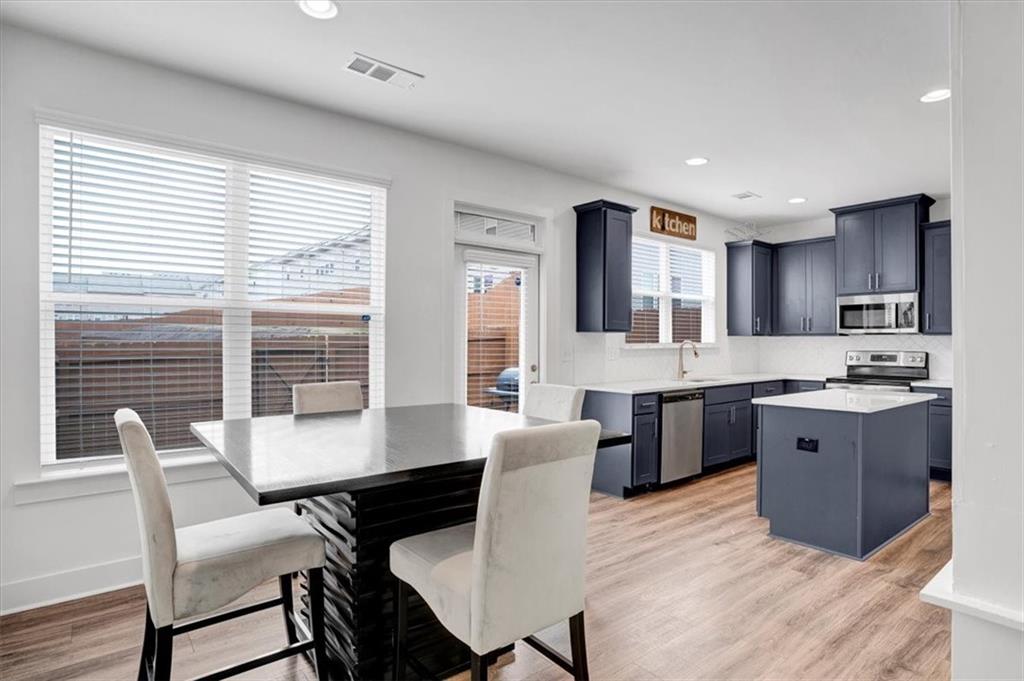 7788 Baron Road Fairburn, GA 30213 - Photo 5 of 17 a large kitchen with kitchen island a dining table chairs and a wooden cabinets