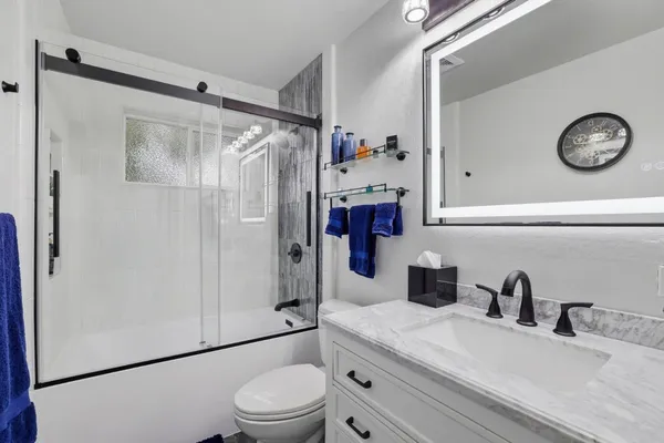 a bathroom with a granite countertop sink a toilet and a shower