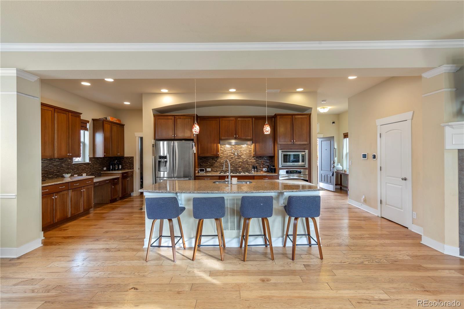 2907 Ironton Street Denver, CO 80238 - Photo 6 of 29 a kitchen with stainless steel appliances kitchen island granite countertop a refrigerator a stove a sink a dining table and chairs with wooden floor