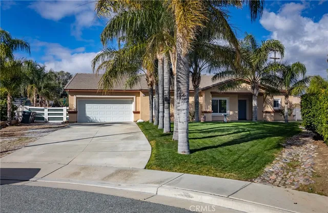 a view of a house with a yard and palm trees