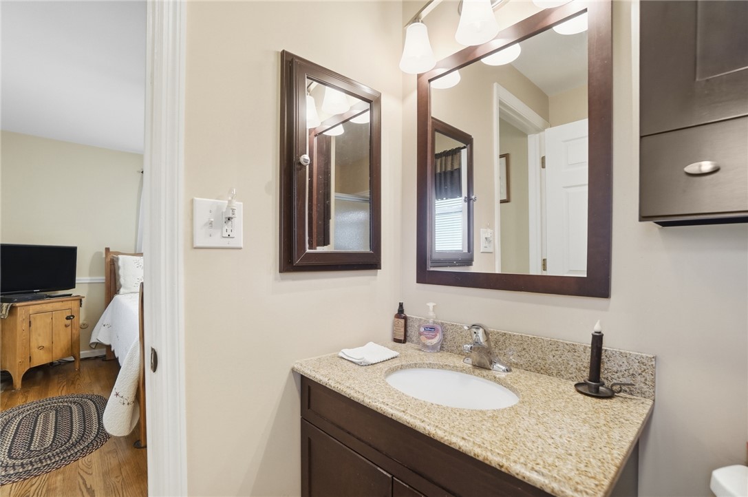 4170 Johnson Road Springfield, OH 45502 - Photo 39 of 54 A well-appointed bathroom vanity with granite counters, offering practical elegance and a glimpse into the adjacent bedroom.