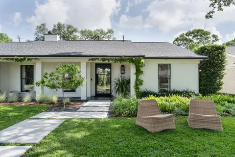 a front view of a house with a yard and potted plants