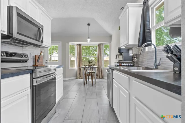 a kitchen with stainless steel appliances granite countertop a stove a sink and a microwave