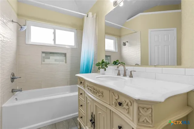 a bathroom with a tub a sink and a mirror