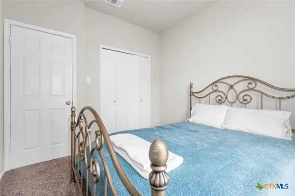 a bedroom with a bed a dresser and potted plant