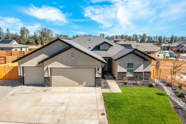 a view of a white house next to a yard with big trees